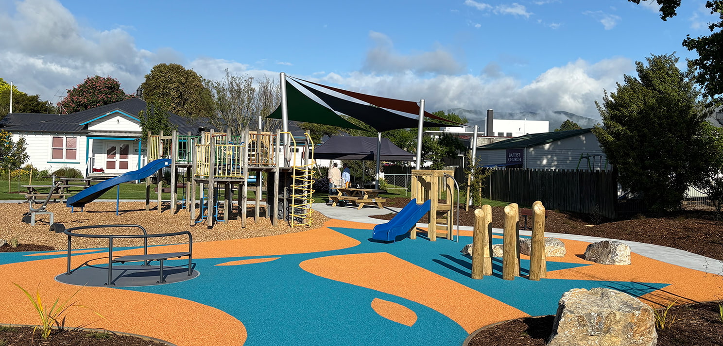 Inclusive playground at Decks Reserve with climbing structures, slides, shade sails, and blue and orange rubber surfacing
