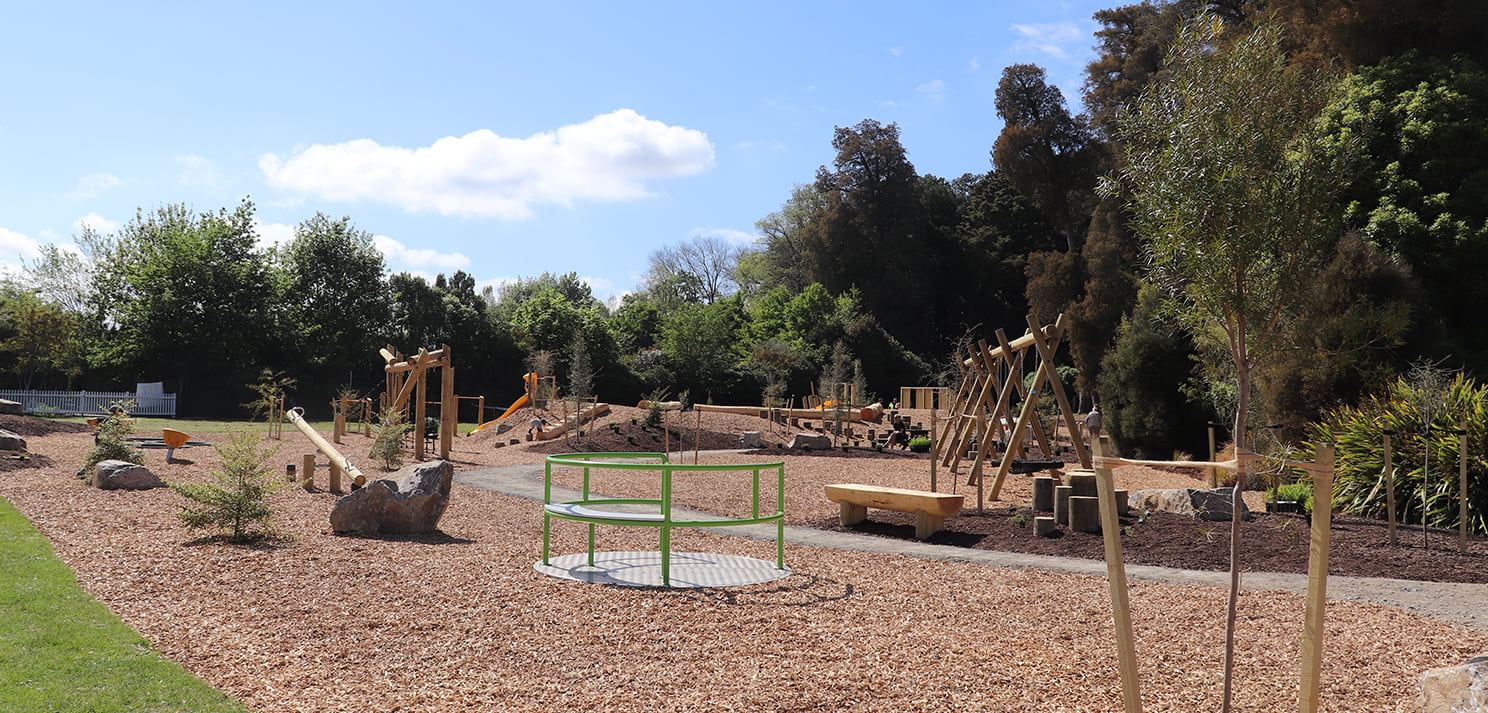 Inclusive carousel surrounded by natural play features at Faulkner Bush Scenic Reserve