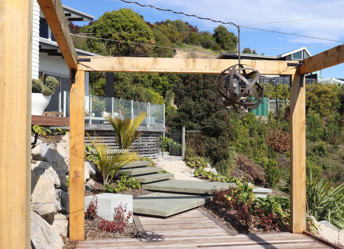 Timber pergola framing stepped walkway through landscaped hillside garden at Maitai Residence