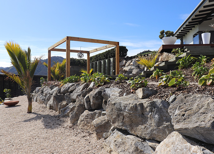 Stone retaining wall and upper garden terrace with pergola at Maitai Residence