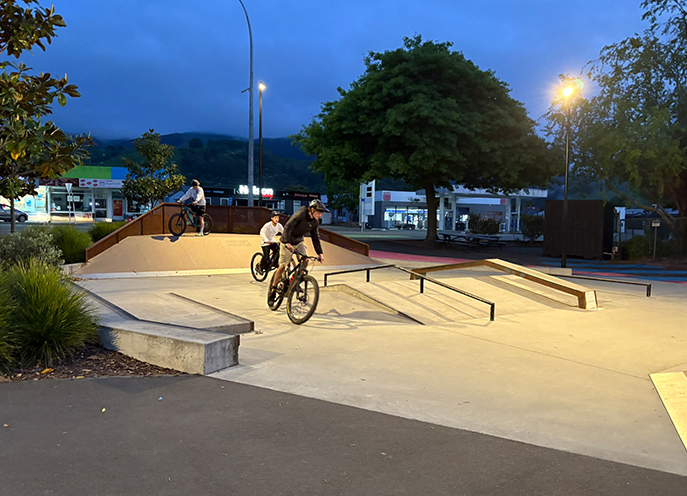 BMX riders moving through ramps and rails at Stoke Youth Park in the evening