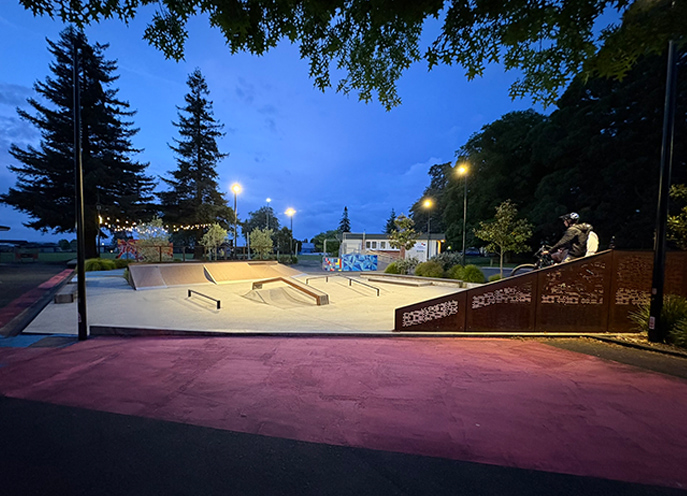 Concrete skate park with ramps, rails, and planting at Stoke Youth Park during the night