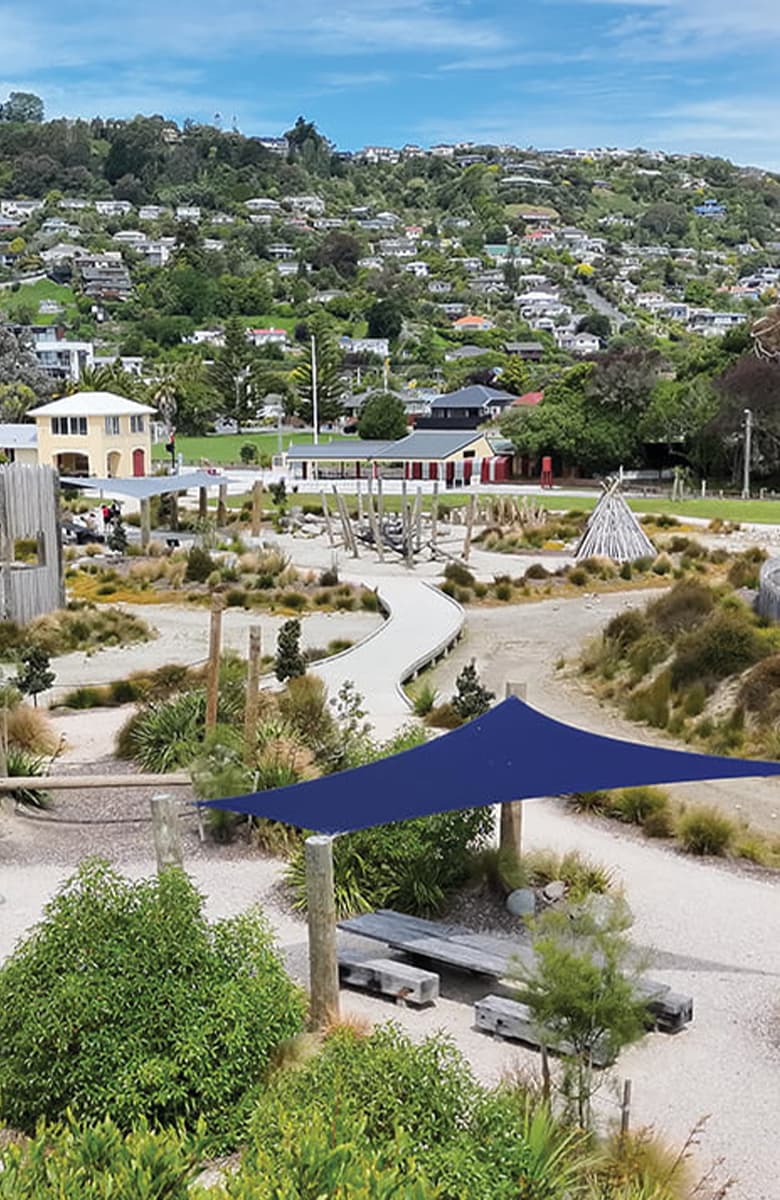Elevated view of seating beneath a shade sail overlooking the Te Pā Harakeke playspace