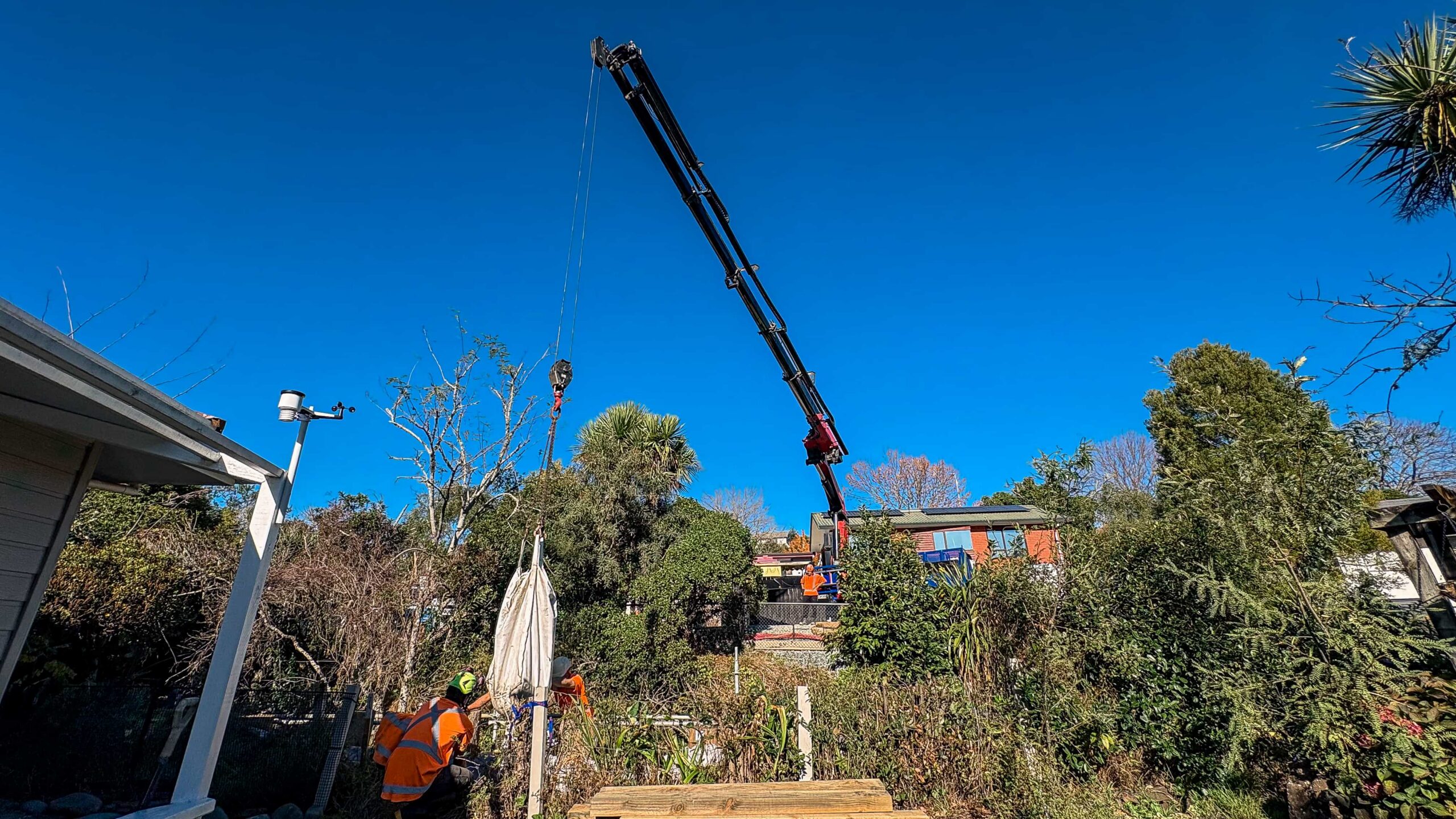 Crane lifting materials into a constrained streambank protection site near Scotia Street